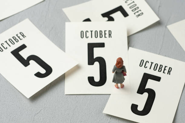 Teacher figurine looking at calendar leaves. "World Teachers' Day" concept.