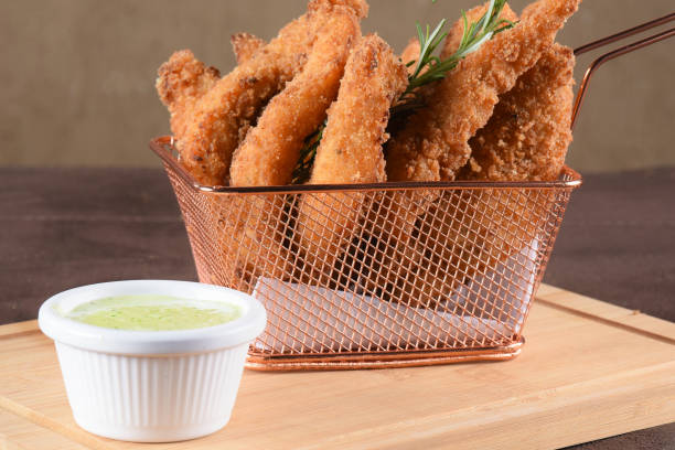 portion of fried fish, fried chicken strips inside metal basket tasty snack