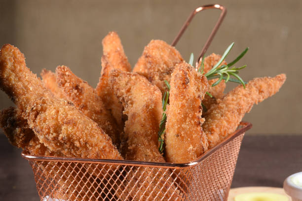 portion of fried fish, fried chicken strips inside metal basket tasty snack