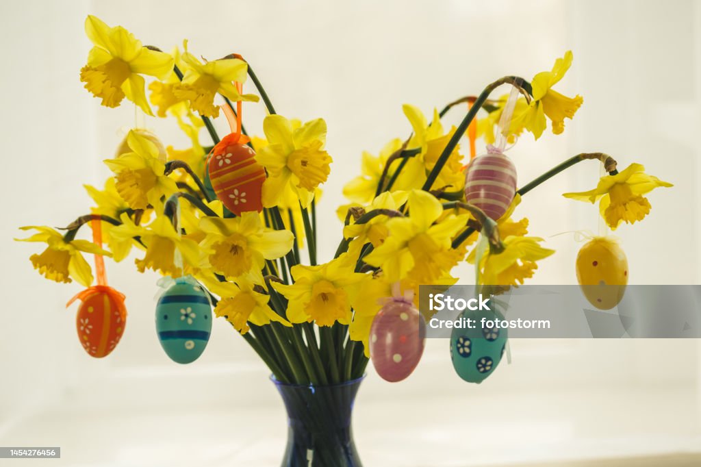 One more option to decorate during Easter Front view of flower arrangement with colorful Easter eggs hanging. Arrangement Stock Photo