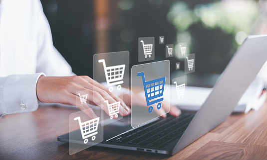 Man using laptop and shopping cart icon,Consumer society,shopaholism concept,Shopping service on The online web and offers home delivery,Connecting merchants and customers around the world