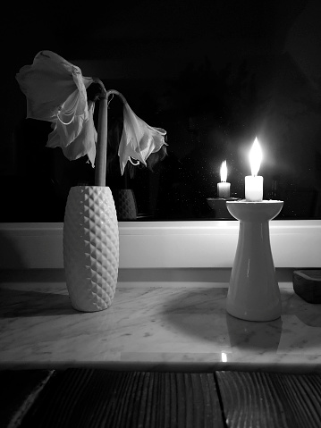Still life of a vase of flowers and a candle. Black and white, strong contrast