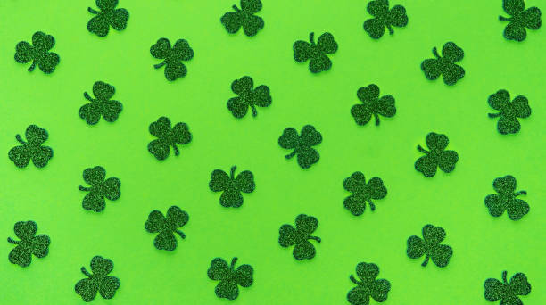 Shamrock background for St. Patrick's Day. Green clover leaves pattern for St. Patrick's Day background. Glitter shamrock leaves on a green matte background.