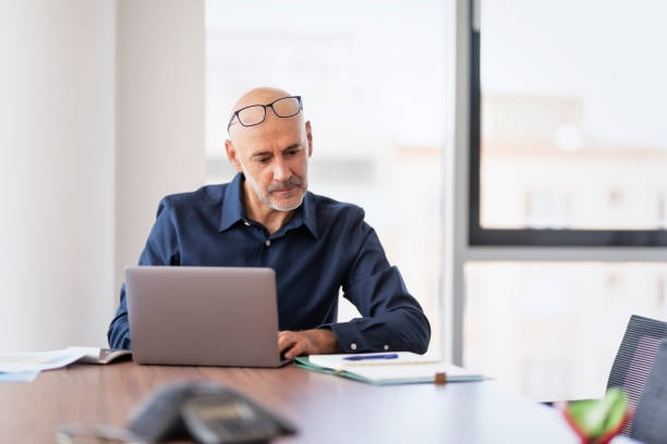 istock Businessman looking thoughtfully while sitting at the office and working on laptop 1454287022