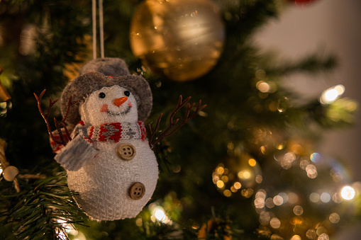 Christmas Scene. A snowman toy is hanging on the tree. Copy space. Christmas background.