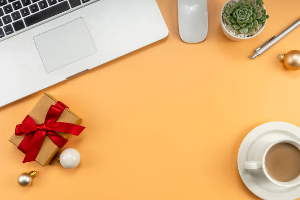 istock Christmas office table with coffee cup, laptop, Xmas decorations on yellow background. Flat lay, top view. New Year workspace. 1454291119