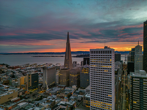 Aerial view over San Francisco with a burning sunrise over the Bay. Skyscrapers fill the skyline.