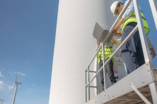 istock Asian engineer working in fieldwork outdoor. Workers check and inspect construction and machine around building project site. Wind turbine for electrical of clean energy and environment sustainable. 1454295885
