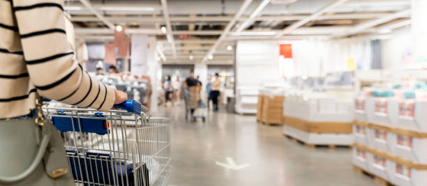 Soft focus woman with shopping cart at store, for furniture in warehouse. Many big metal shopping carts for the interior furniture stock photo