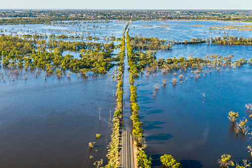 Aerial view flooded tree-lined Bookpurnong Road, the main Loxton to Berri connector road on River Murray in South Australia: flooded Gurra Gurra floodplain, bridge over Gurra Gurra Creek in centre frame, town of Berri in the distance on tree-covered hills, River Murray just visible in distance.