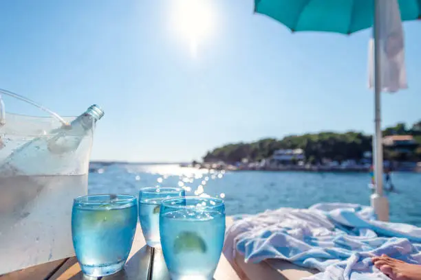 Photo of Glasses of Water and a bottle at the beach.