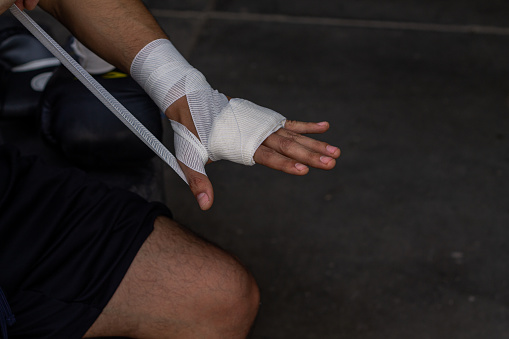 A closeup of a Hispanic man tying a bandage around his hand.