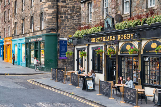 People sit on the patio of the historic Greyfriars Bobby pub in Old Town Edinburgh, Scotland on a cloudy day.