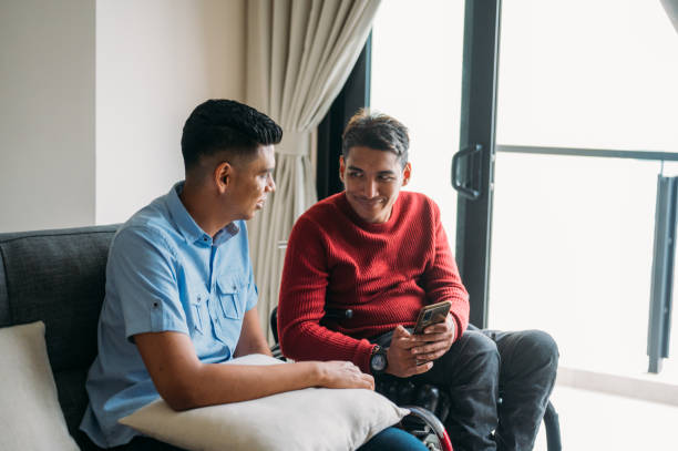 istock An Asian disabled man and his co-worker using smartphone greeting colleagues via video call at living room. 1454316638
