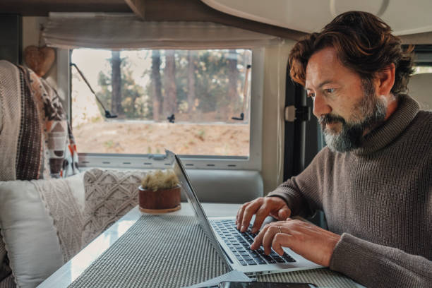 istock One man working on laptop computer inside camper van in alternative office and job lifestyle. Freedom in smart working people. Digital nomad van life. Travel and using computer technology with roaming 1454316901