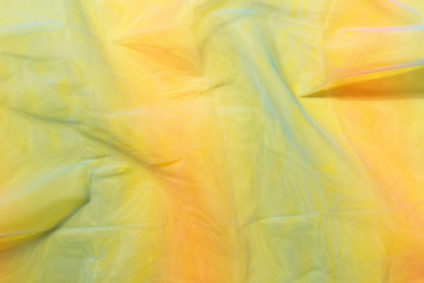 istock Silk fabric transparent. Yellow twisted twirl fabric multicolour texture 1454320875
