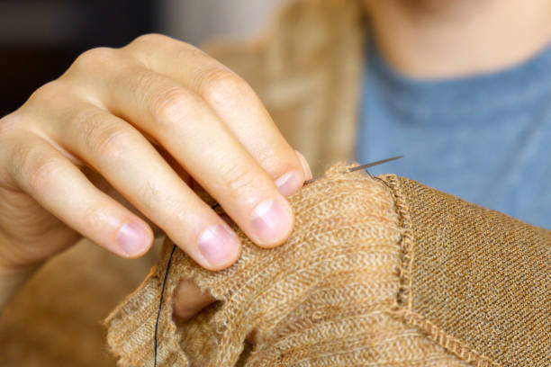istock Hands men close-up. Mending clothes, sewing and darning, and fashionable needlework. Selective focus 1454321058