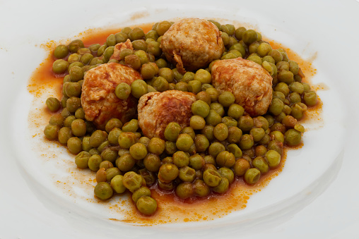 Beef meatballs with peas garnish in white plate isolated on white bakground