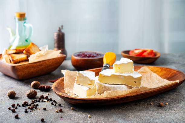 istock Camembert cheese with figs, raspberry jam. Round brie or camambert cheese on cutting board 1454323900