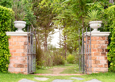 An arched blue garden gate with a walkway lined with flowers.