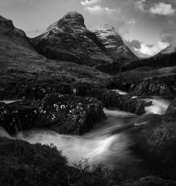 istock Black and white view of a long exposure river flowing through mountainous fields 1454328122