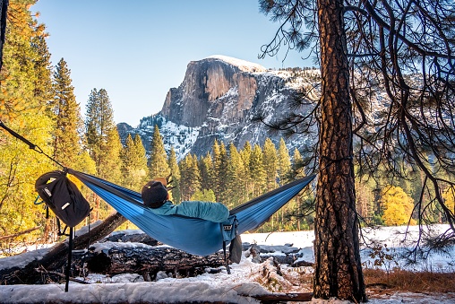 A man in a hammock enjoying the picturesque winter landscape of Half-dome, Yosemite national park