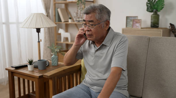 istock senior man sitting on home sofa and answering call on cellphone during retirement time. boring elderly male hanging up after end the conversation on mobile phone while relax on couch in living room 1454330870