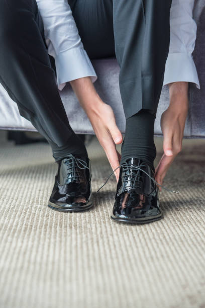 istock Groom wearing his shoes and getting ready for his wedding 1454331510