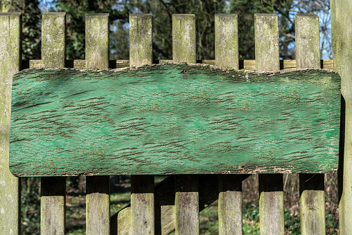 A closeup shot of a green wooden sign on a bridle, which is already slightly weathered