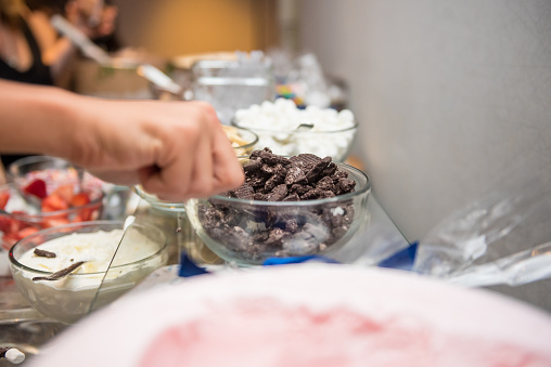A guest taking crushed chocolate cookies from the dessert table bar
