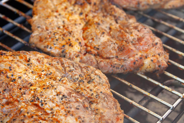 Food, bbq and zoom of steak on grill, smoke and flame at fun social gathering and weekend time. Flipping meat, cooking and outdoor grilling on fire in garden for barbecue party or cookout at home.