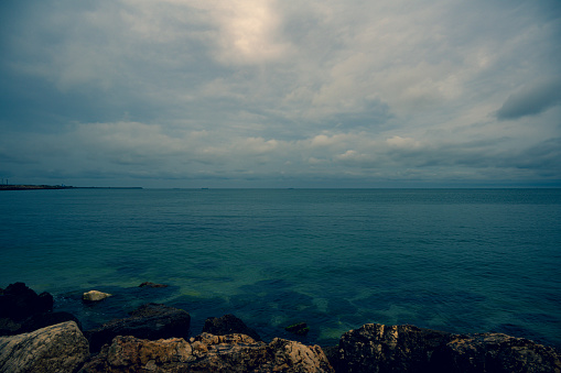 A beautiful scene of a sea shore in a cloudy day with a gray sky on the horizon