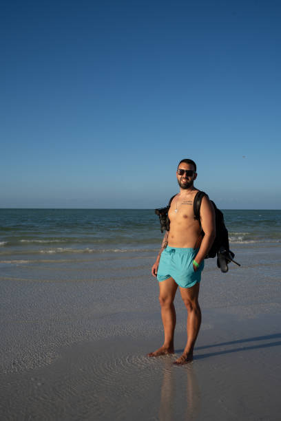 istock Young male tourist strolling along Holbox beach with a bathing suit and camera 1454337031