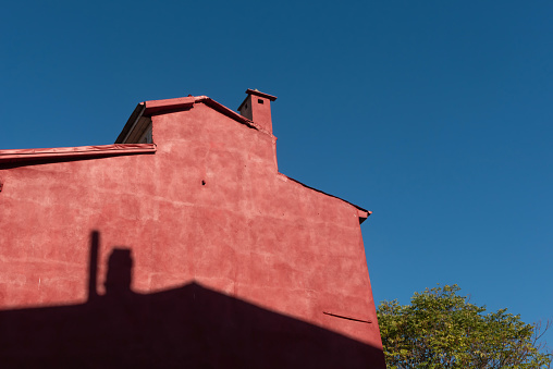 An old red stone building with a chimney against a blue sky on a sunny day