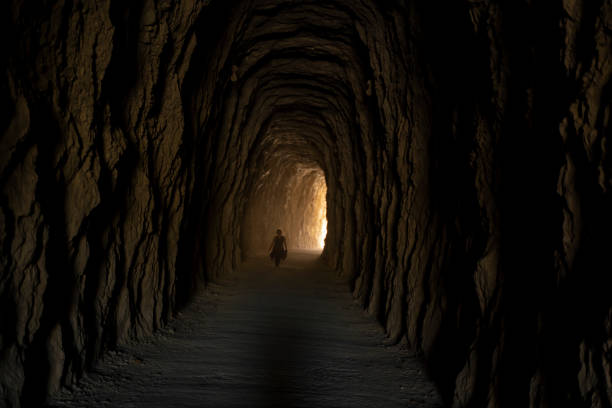 istock View of a person crossing a deep cave tunnel 1454337768
