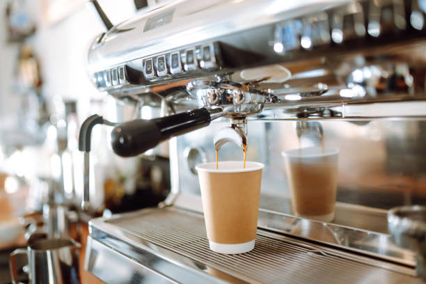 istock Hot delicious coffee pouring from coffee machine into coffee cup. 1454337891