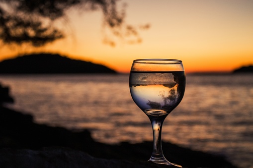 A selective focus of a glass of water reflecting the sea at sunset