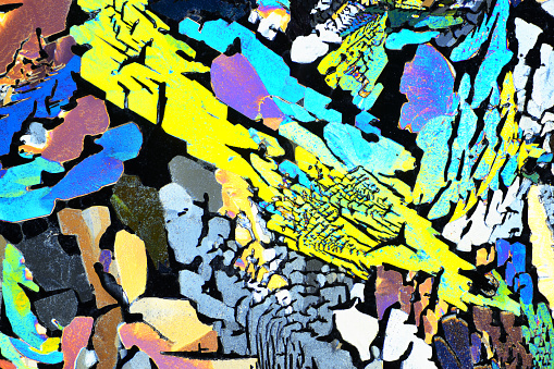 Photo through a microscope of crystals grown from a melt of citric acid. Polarized light technology. Abstract art wallpaper. Background for design.