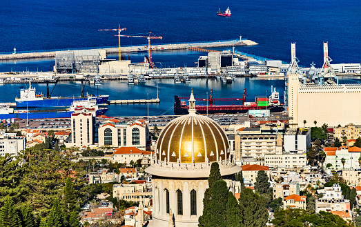 Haifa, Israel - December 2022: View of Shrine of the Bab, the harbor port of Haifa and port cranes, cargo containers and ships in a sunny winter day. Haifa, Northern Israel.