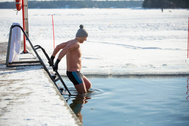 A man in warm hat and gloves swimming in an ice hole stock photo