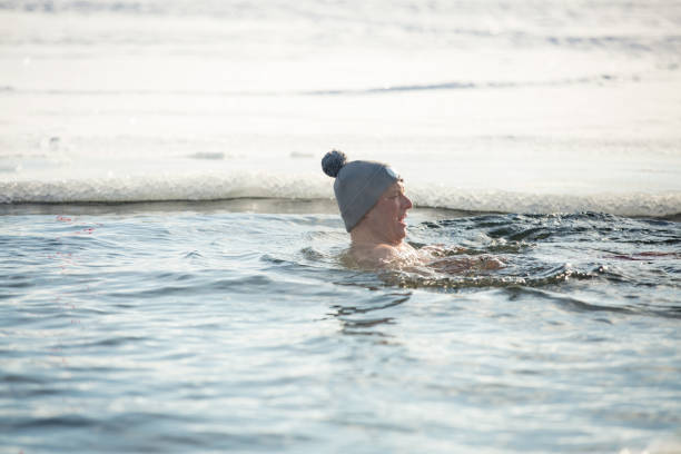 istock A man in warm hat swimming in an ice hole 1454339595