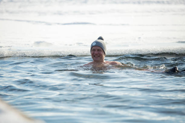istock A man in warm hat swimming in an ice hole 1454339597