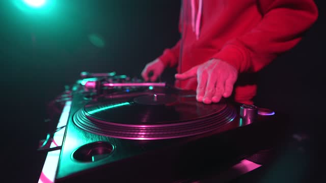 Hip hop DJ scratches vinyl record on turntables. Disc jockey scratching records on party in night club