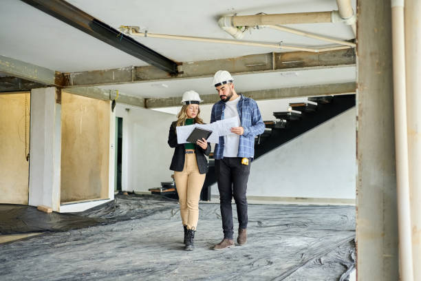 istock Two civil engineers discussing on blueprints walking at under construction site 1454341992
