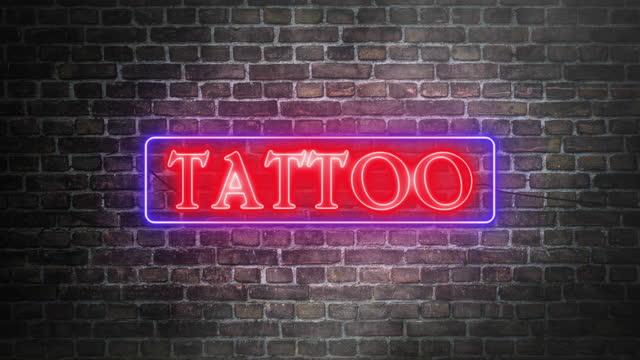 Tattoo shop neon real sign on bricks wall background. Blue frame neon and red letters. Concept of storefront. Realistic symbol sign of tattoo shops.
