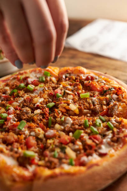 istock Vertical shot of pizza with a hand grabbing it 1454343724
