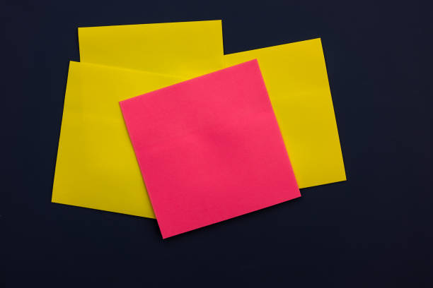 istock blank pink square sticky note on many yellow square sticky notes, top view. Blank space for future important events announcements 1454346031