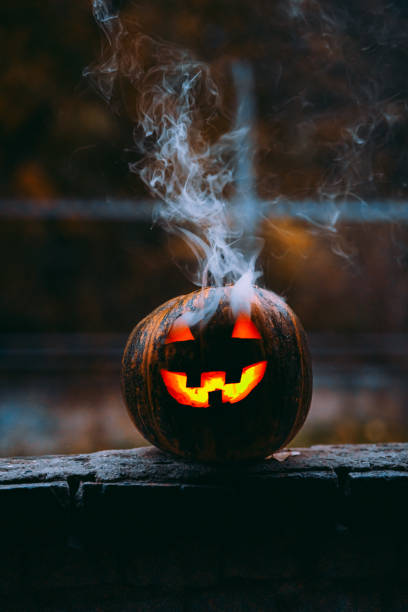 istock Vertical shot of an illuminated scary jack-o-lantern with smoke 1454346163