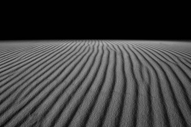 istock Grayscale shot of textured sand dunes on a beach 1454347063