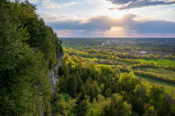istock Sun slowly plunging through the clouds as seen from a tree-lined cliff 1454347855